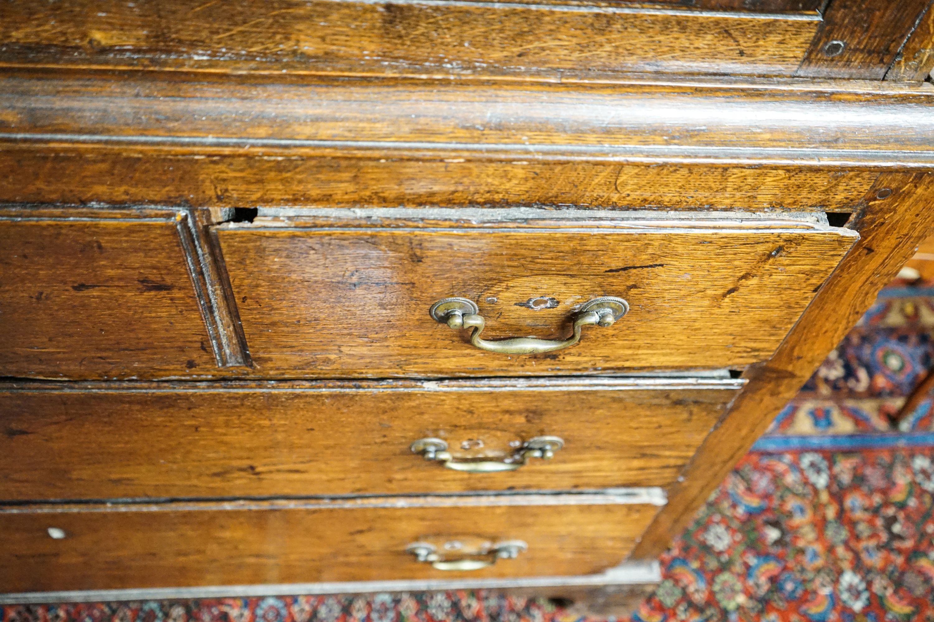 A George III oak press cupboard, with moulded cornice and two panelled doors over five drawers, width 122cm, depth 52cm, height 183cm